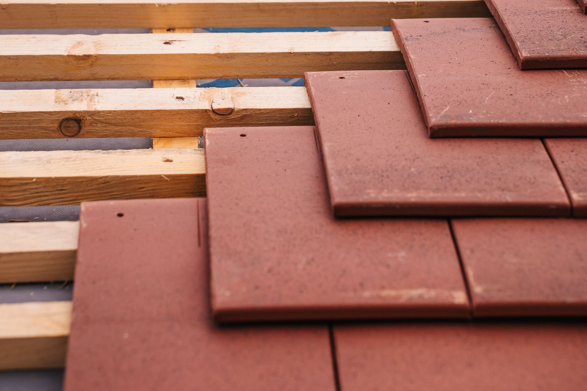Clay_Tile_Underlayment_Renewal Close-up of clay tiles being laid on new battens over fresh roof underlayment