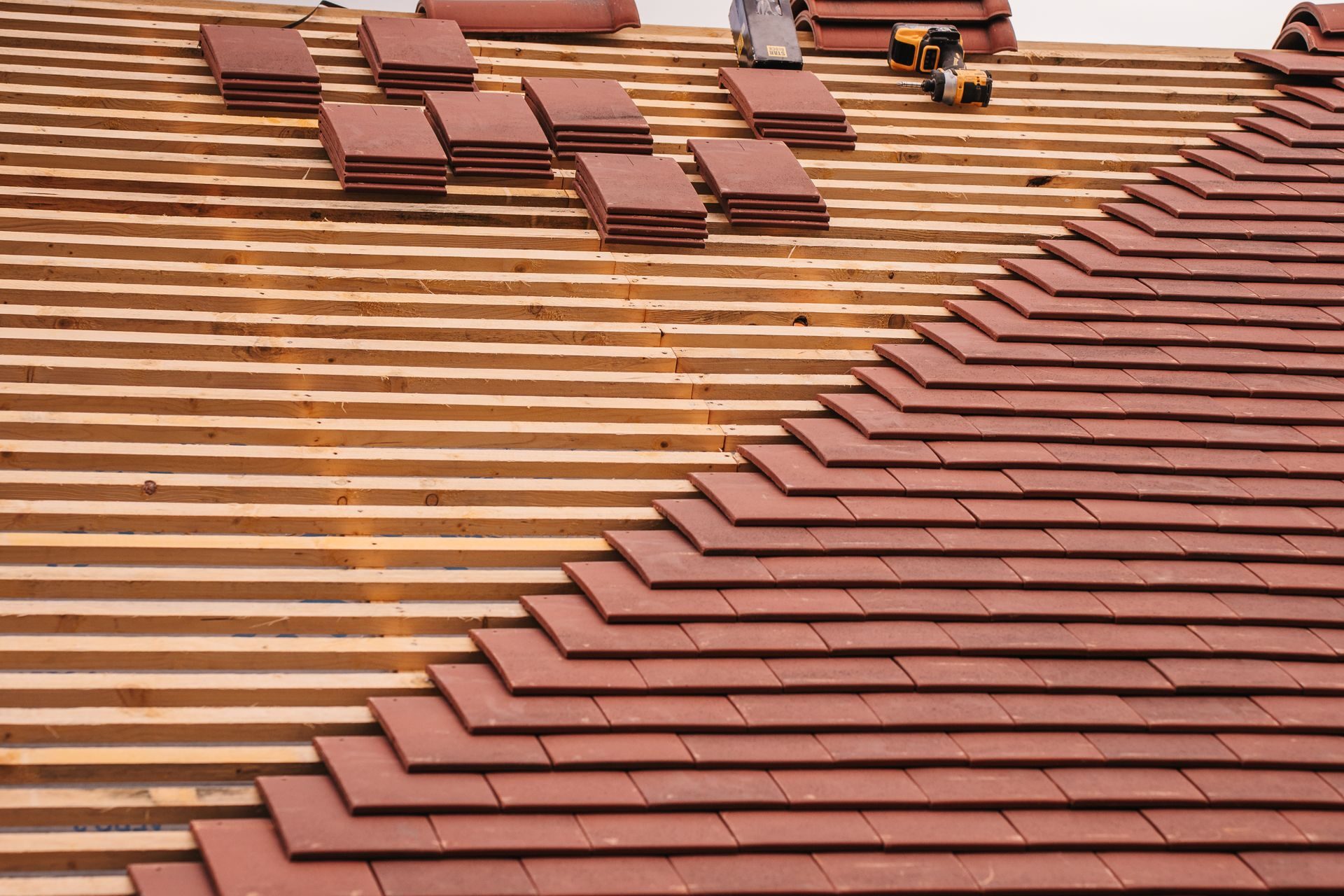 Clay tiles being relaid over new battens and underlayment on a sloped roof